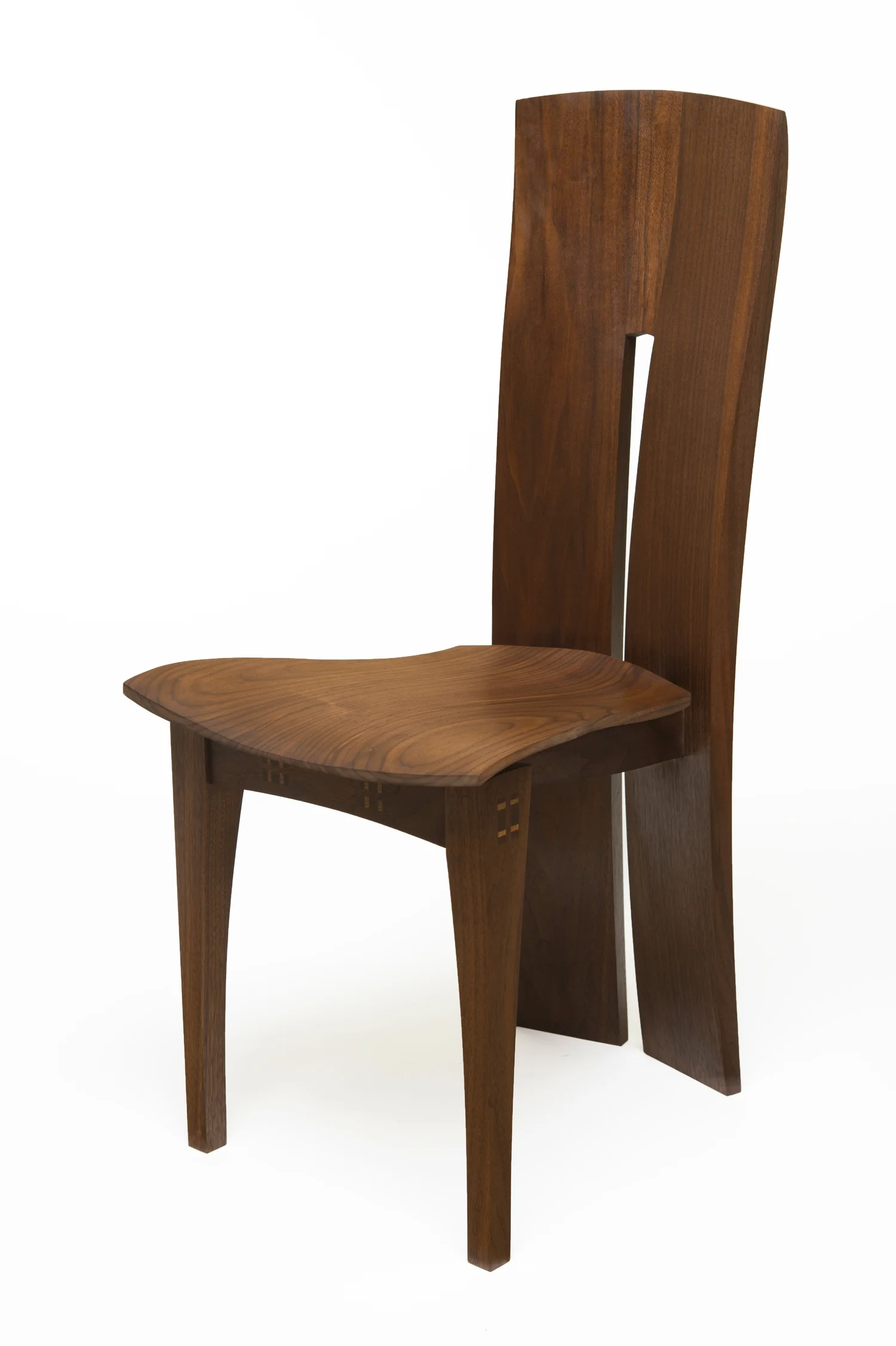 A high-backed walnut dining chair with a sculpted seat and split back