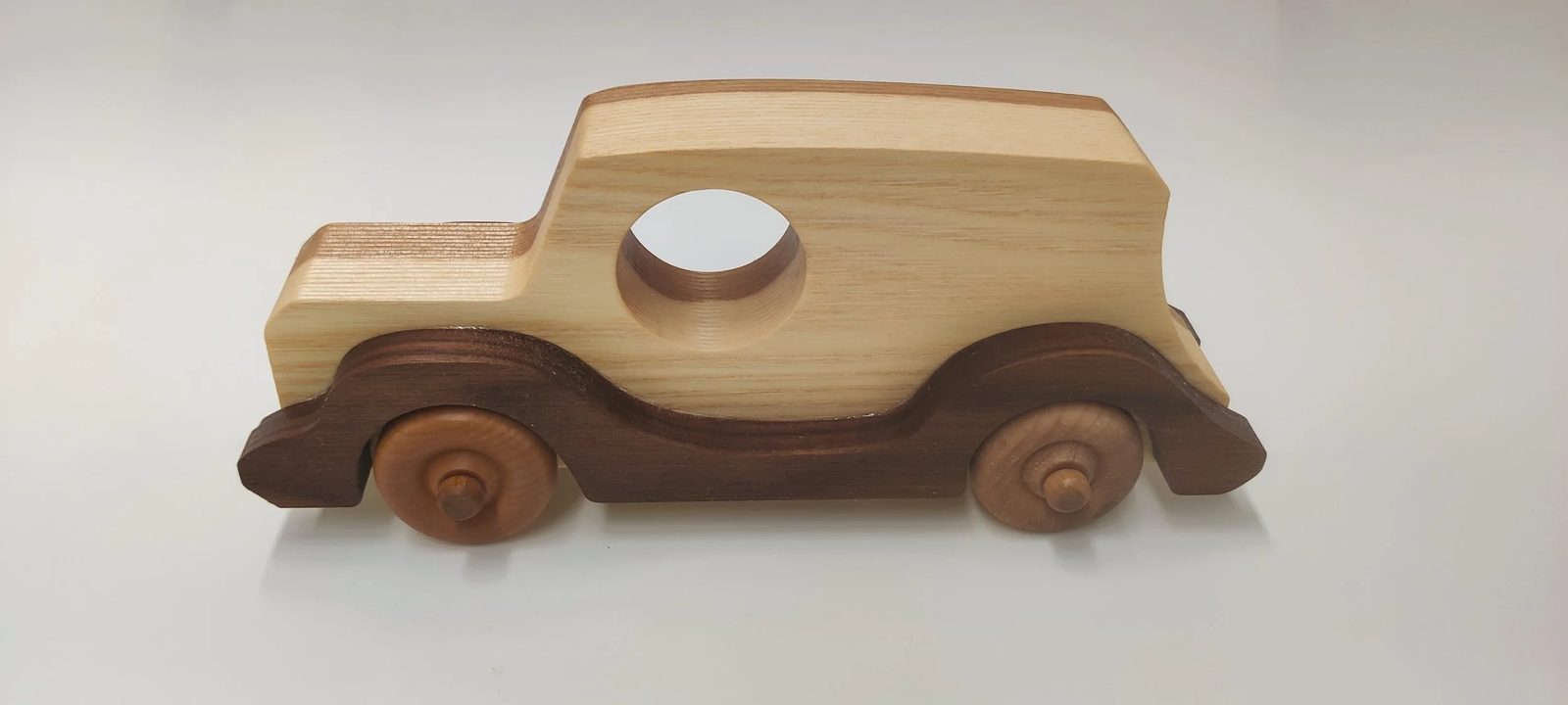 A two-tone wooden toy car in ash with walnut fenders