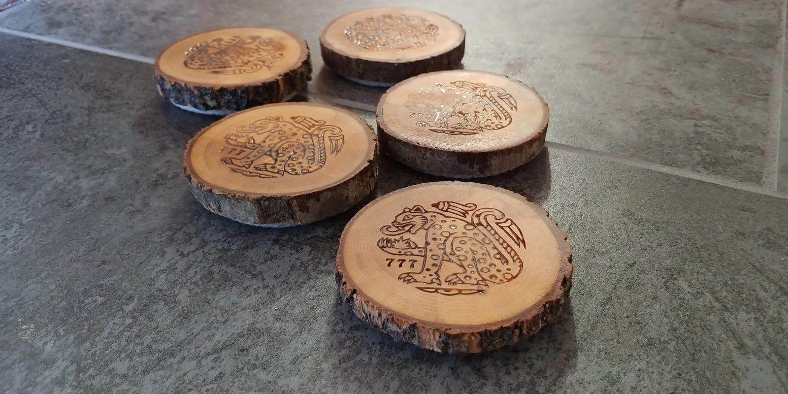 Five live-edge wooden coasters engraved with a jaguar design