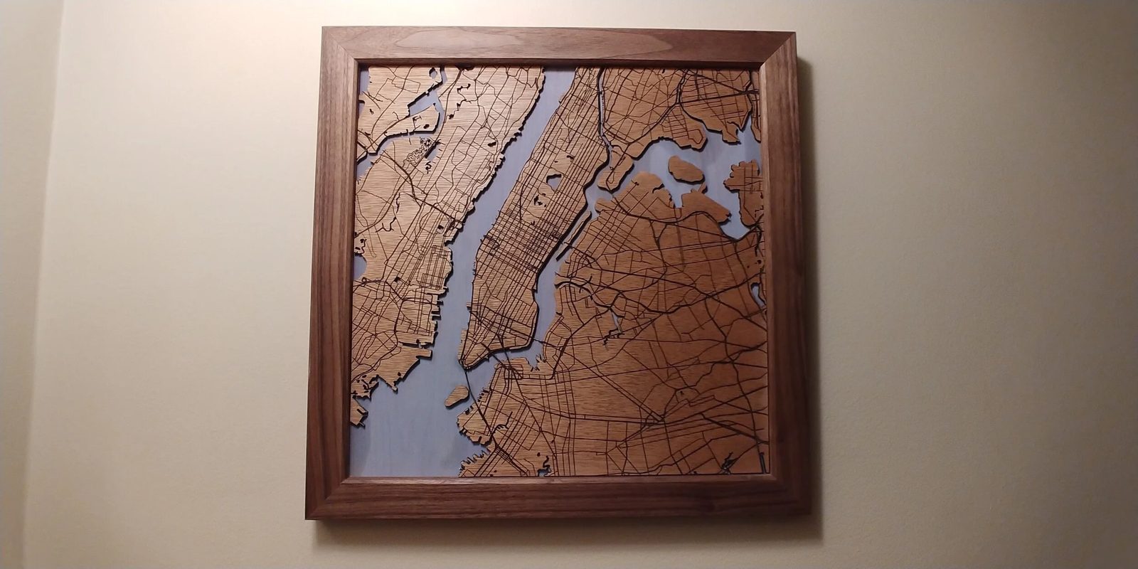 A framed laser-cut map of the New York harbor in layered oak and walnut