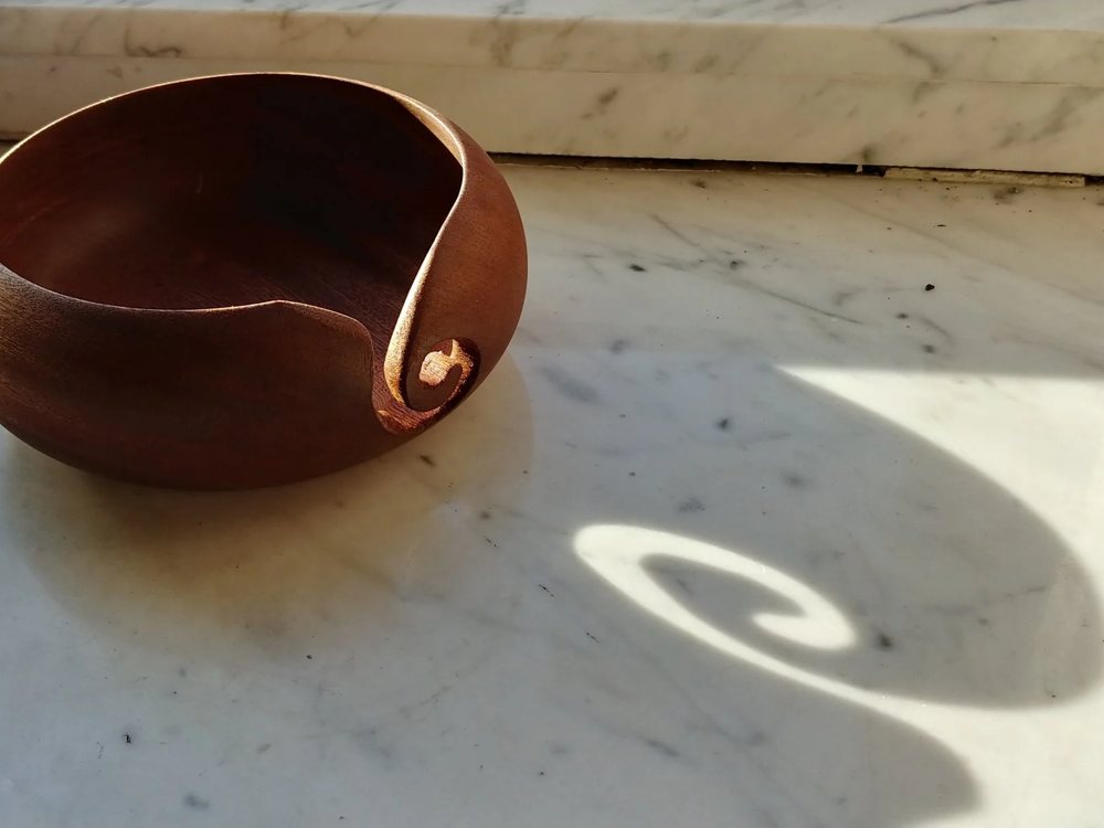 A turned hardwood yarn bowl on a sunlit sill